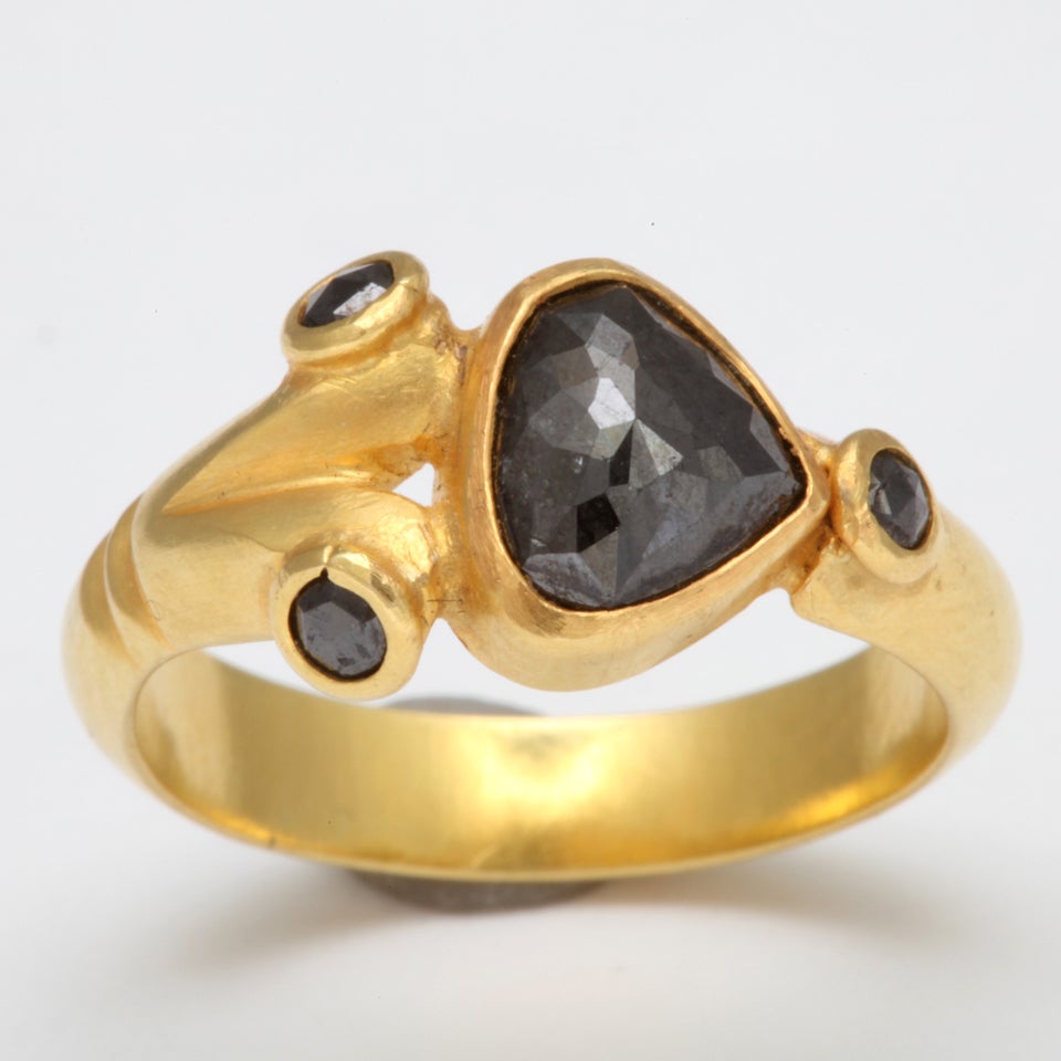 An 18kt yellow gold ring set with three round black diamonds and a rose cut pear shaped black diamond. Total diamond weight: 2.47cts
