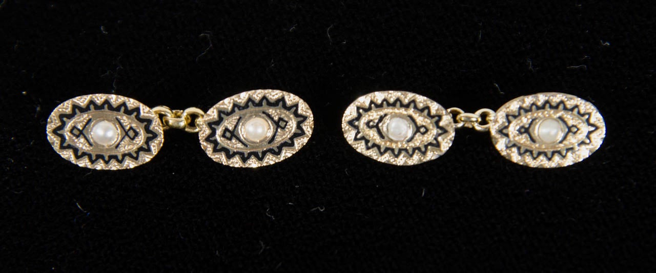 These 14k yellow gold cufflinks feature a pearl set in the center with an Art Deco black enamel geometric design.