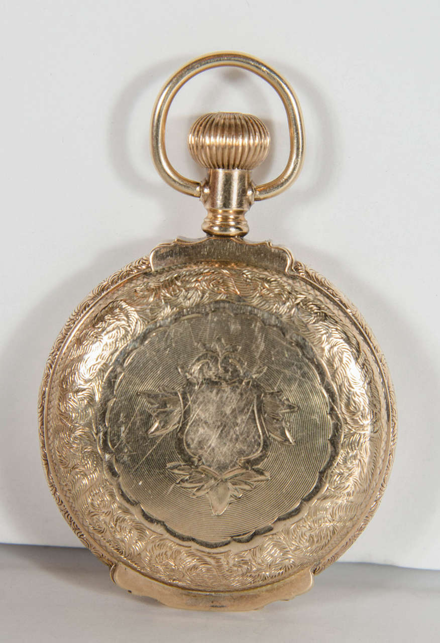 This beautifully hand engraved pocket watch features a shield design with stylized foliage neoclassical detailing. It is made of 14k yellow gold. It features the original face in excellent condition and bears the signature Waltham 