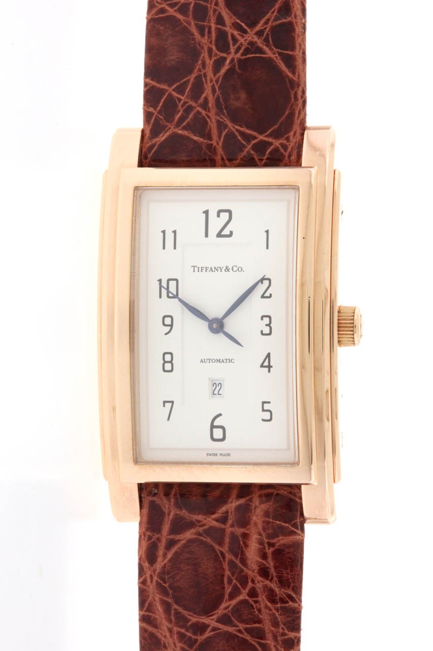 18k rose gold Tiffany & Co 'Grand' automatic rectangular wristwatch with center seconds and date. Elegant case measuring 30mm x 49mm, with triple stepped bezel, white dial with painted Arabic numerals, blued steel hands, date aperture at 6 o'clock,