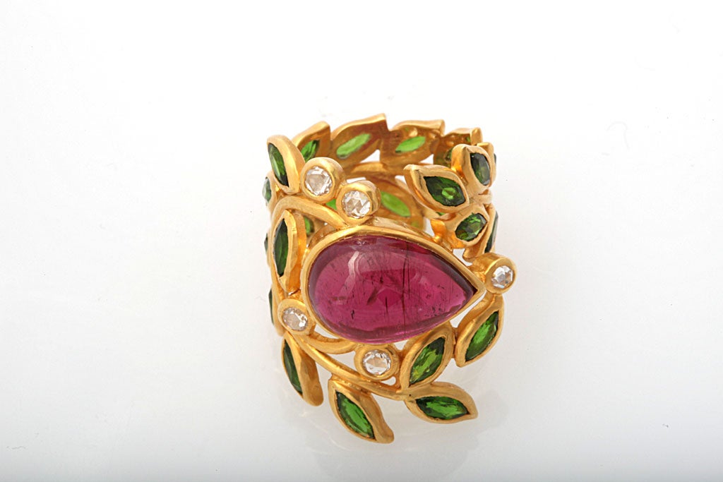 An 18kt yellow gold ring composed of bezel set tsavorite leaves, diamonds and a pear shaped tourmaline.