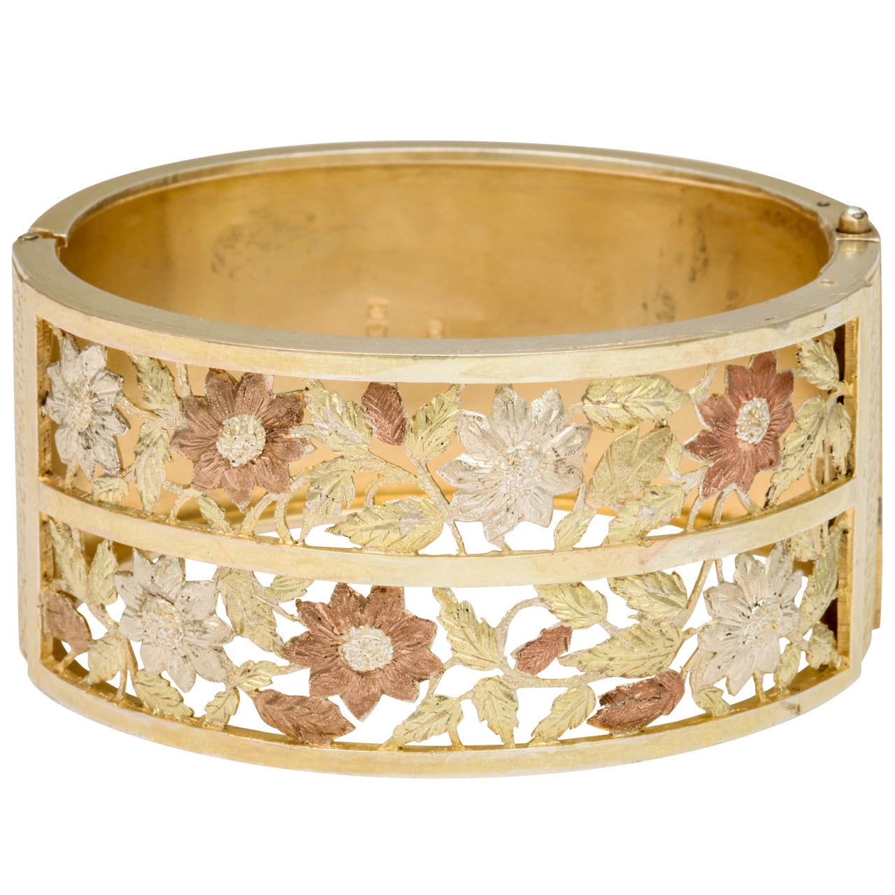 Golden hues fill this bracelet with the intensity of midday sun. Two rows of flowers, with realistic engraving, have been cut from the silver and play among the vines. Crosshatched engraving borders the bracelet sides. The bracelet is English c.