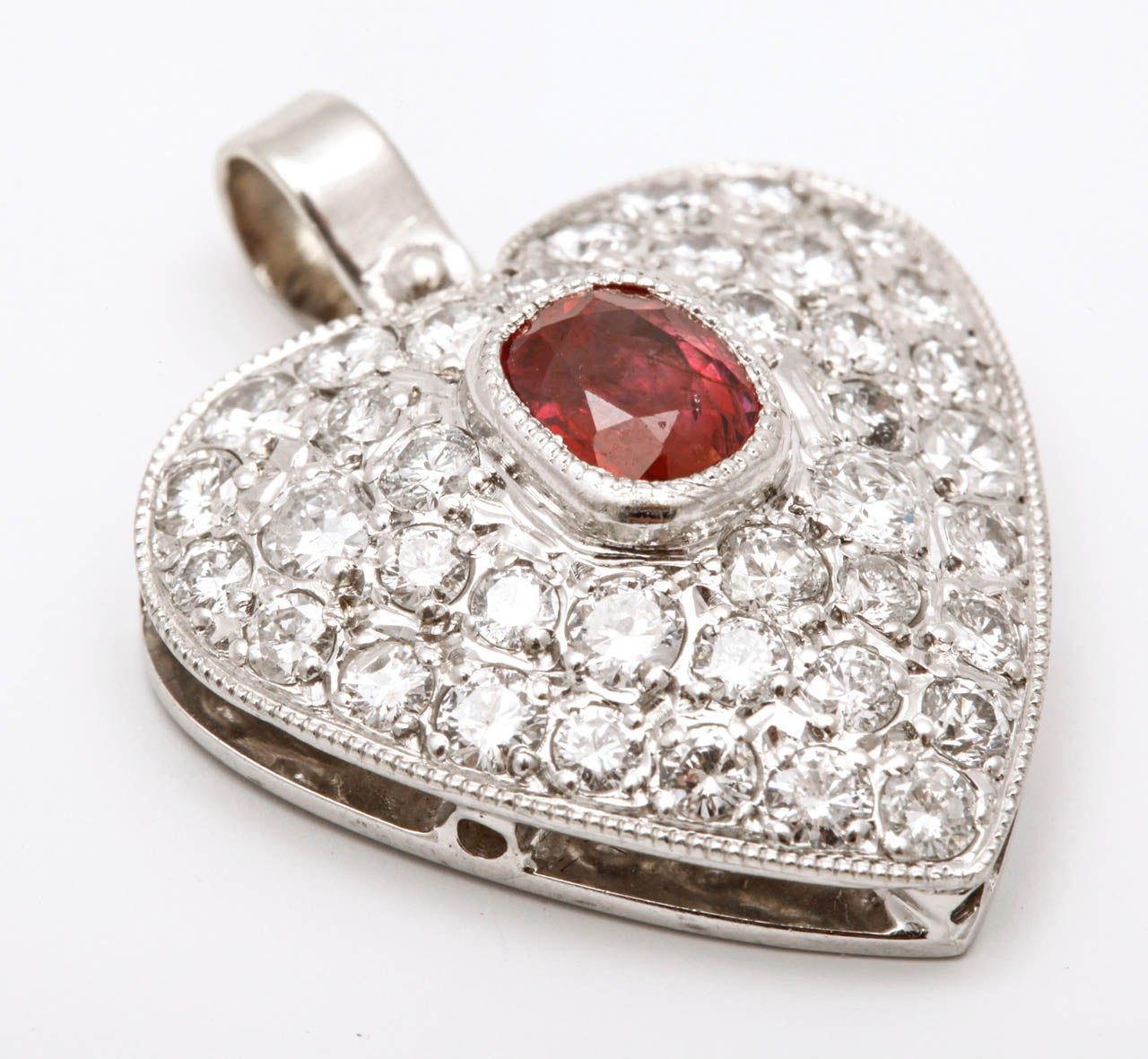 A 14 carat white gold ruby and diamond heart-shaped pendant
Designed as a heart set with an oval-cut ruby to a surround of pavé-set brilliant-cut diamonds with a total weight of approximately 2.90 carats.

All of our prices exclude VAT.