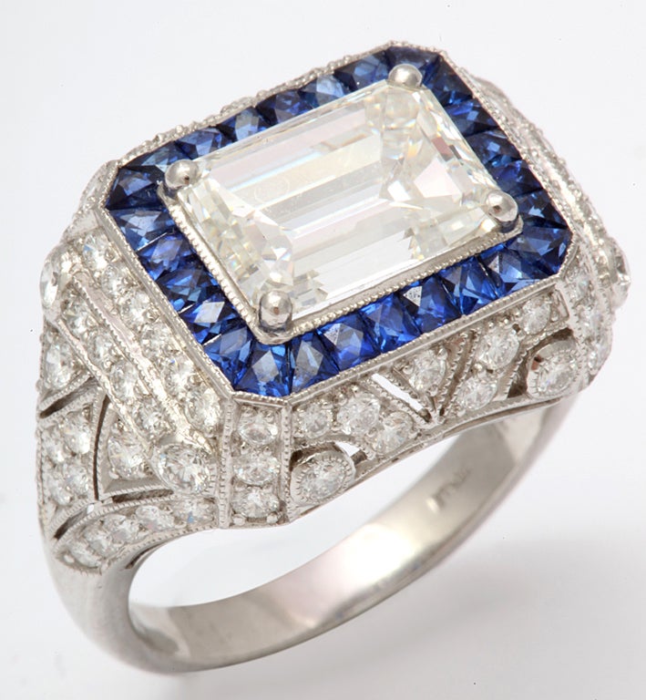 Art Deco style ring featuring one emerald cut diamond weighing 3.02 cts, flanked with sapphires, 2.09 cts and numerous diamonds weighing 1.14 cts, in platinum.