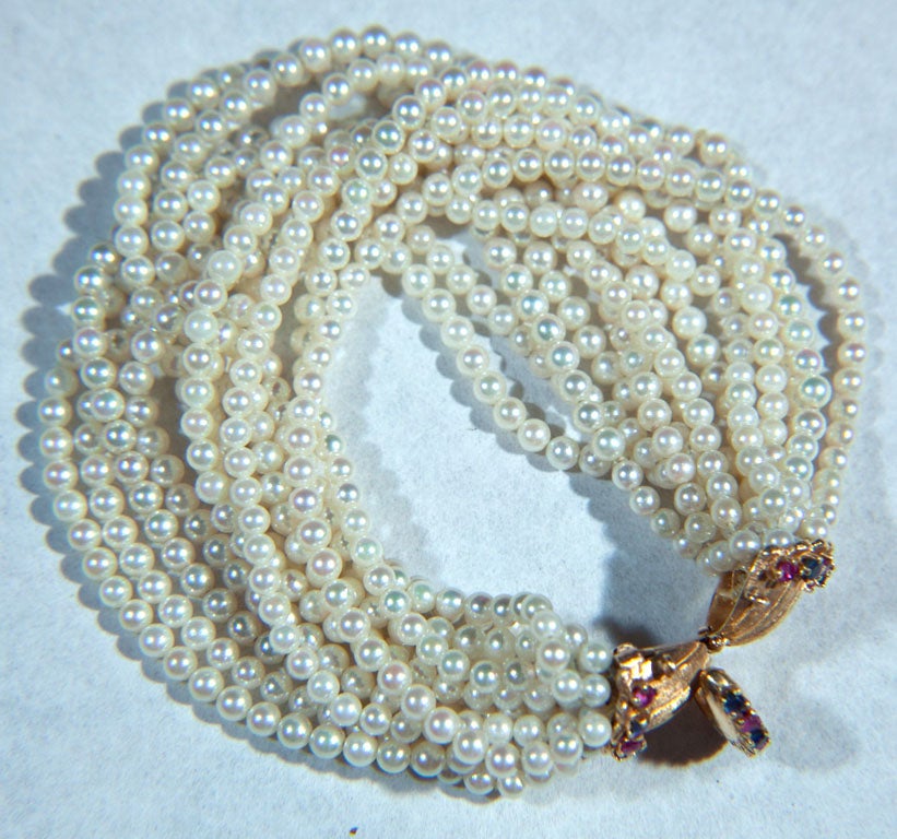 THIRTEEN STRANDS OF CULTURED PEARLS JOINED AT CLASP OF 14K GOLD<br />
GARNET  AND RUBIES