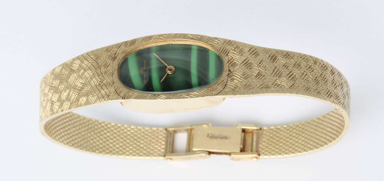 Sleek & elegant 14kt Yellow Gold Baume & Mercier lady's wristwatch with faux malachite enamel face.  Engraved band with adjustable closing