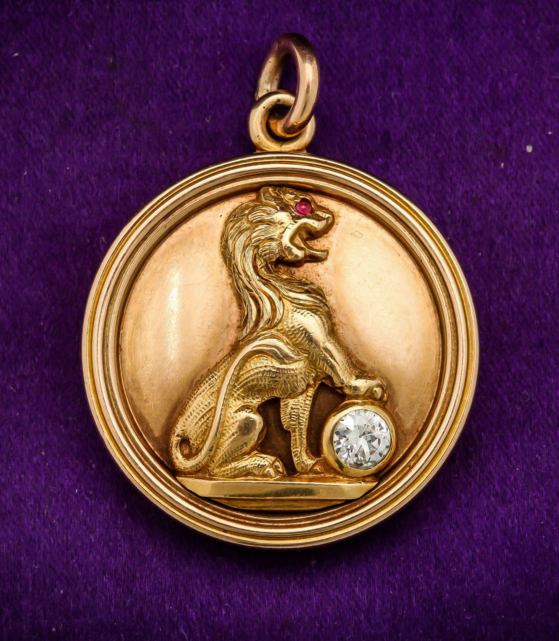 18kt yellow gold double-sided heavy locket designed with a handmade crafted figural lion resting his paw on a .20ct old mine cut diamond with a faceted ruby set in lions eye it may hold two photographs on each side made in the Victorian era in the