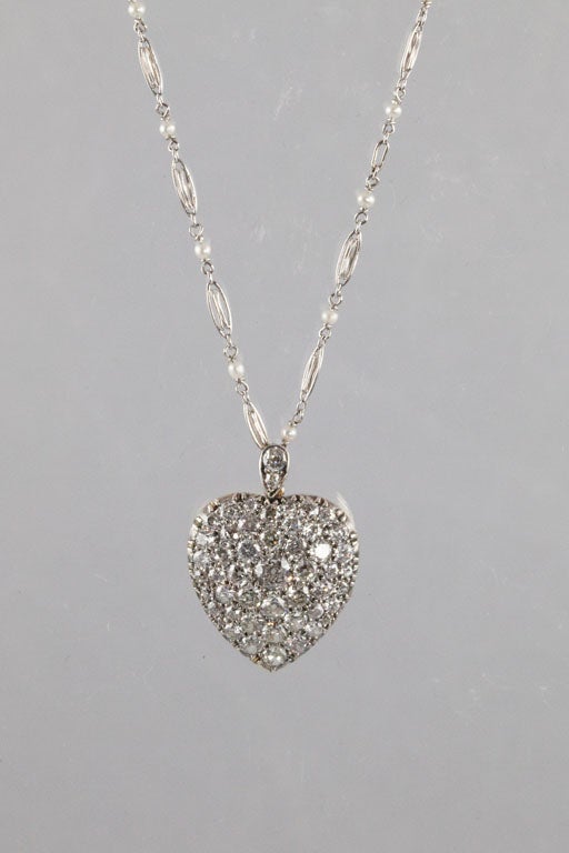The locket is backed in 18 karat gold, topped in silver and contains approximately 4.25 carats of old European and old mine-cut diamonds, color: H-I, clarity: VS1-SI1. The back of the locket has a heart-shaped glass face and opens to hold a picture
