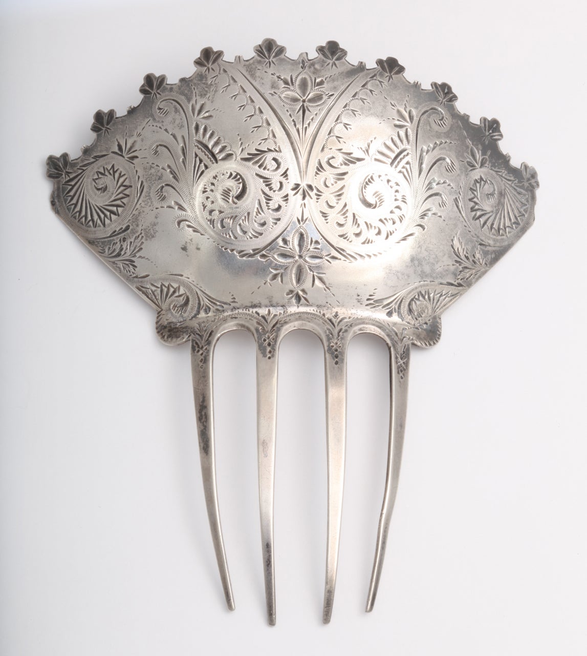 Grand in scale and manner is this large silver hair ornament. Although American, it was made in the youth of the American jewelry industry. It has a bit of Spanish or English flavor. The engraving is florid and swirling. A fabulous decoration for