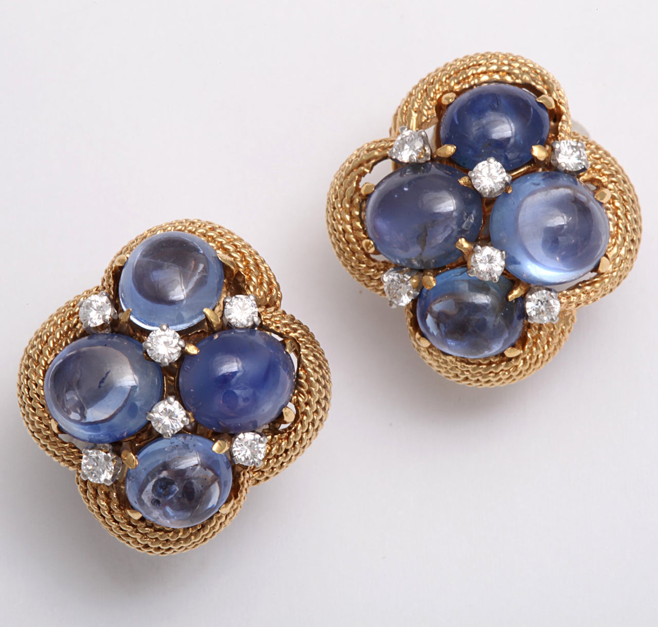 A fabulous early pair of 18 kt gold clip earrings with cabachon sapphires and diamonds surrounded by woven frame. Signed David Webb