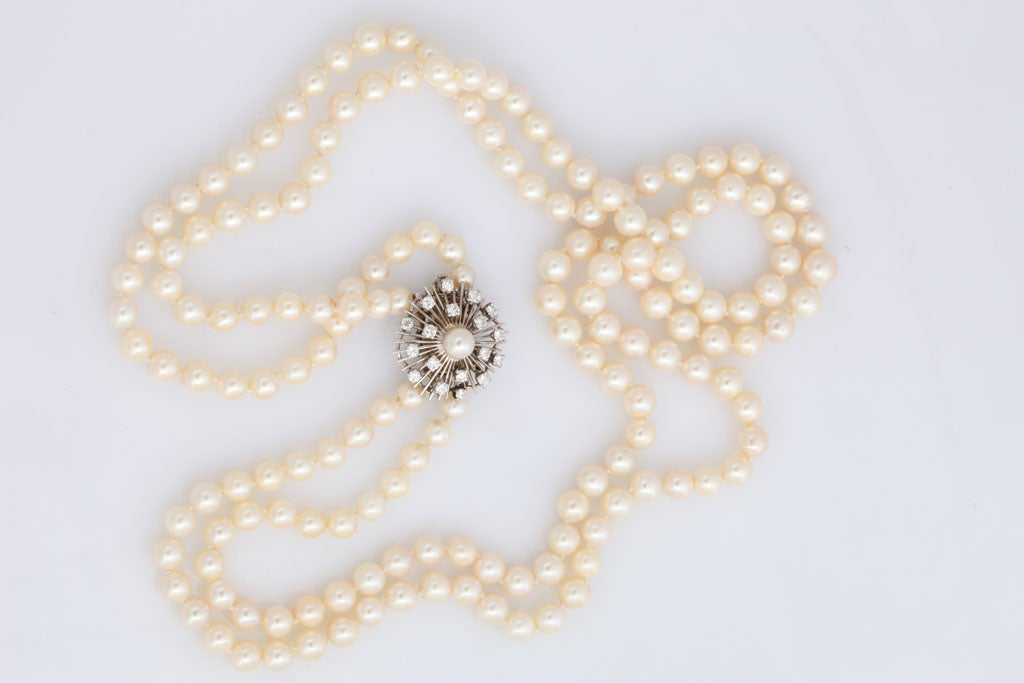 An exquisitely elegant double strand pearl necklace held in place by an 18K white gold starburst decorated with a pearl, and surrounded by diamonds.