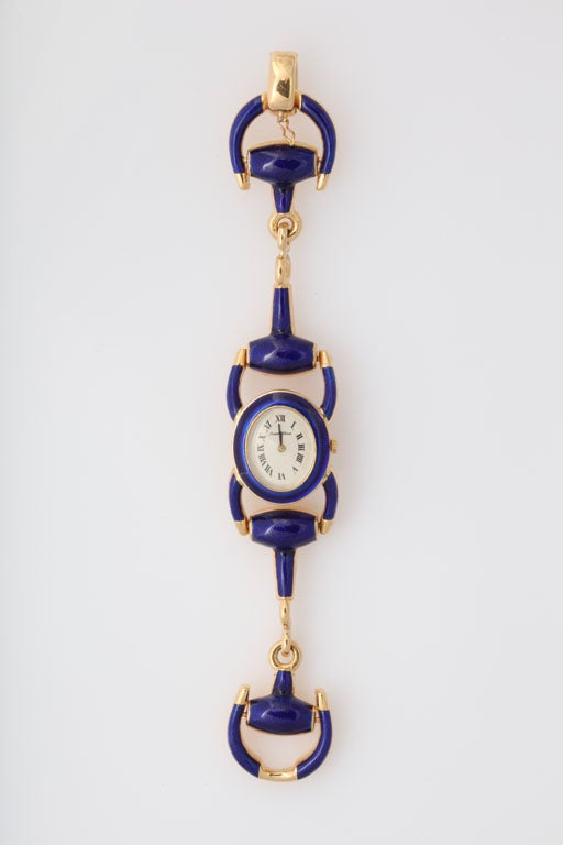 Bueche Girod Lady's Enamel, Gold Integral Stirrup Bracelet Wristwatch centering on an oval white face, the bracelet continuing with fancy solid yellow gold and royal blue enamel stirrup shaped links all around, mounted in 18KT yellow gold; back of