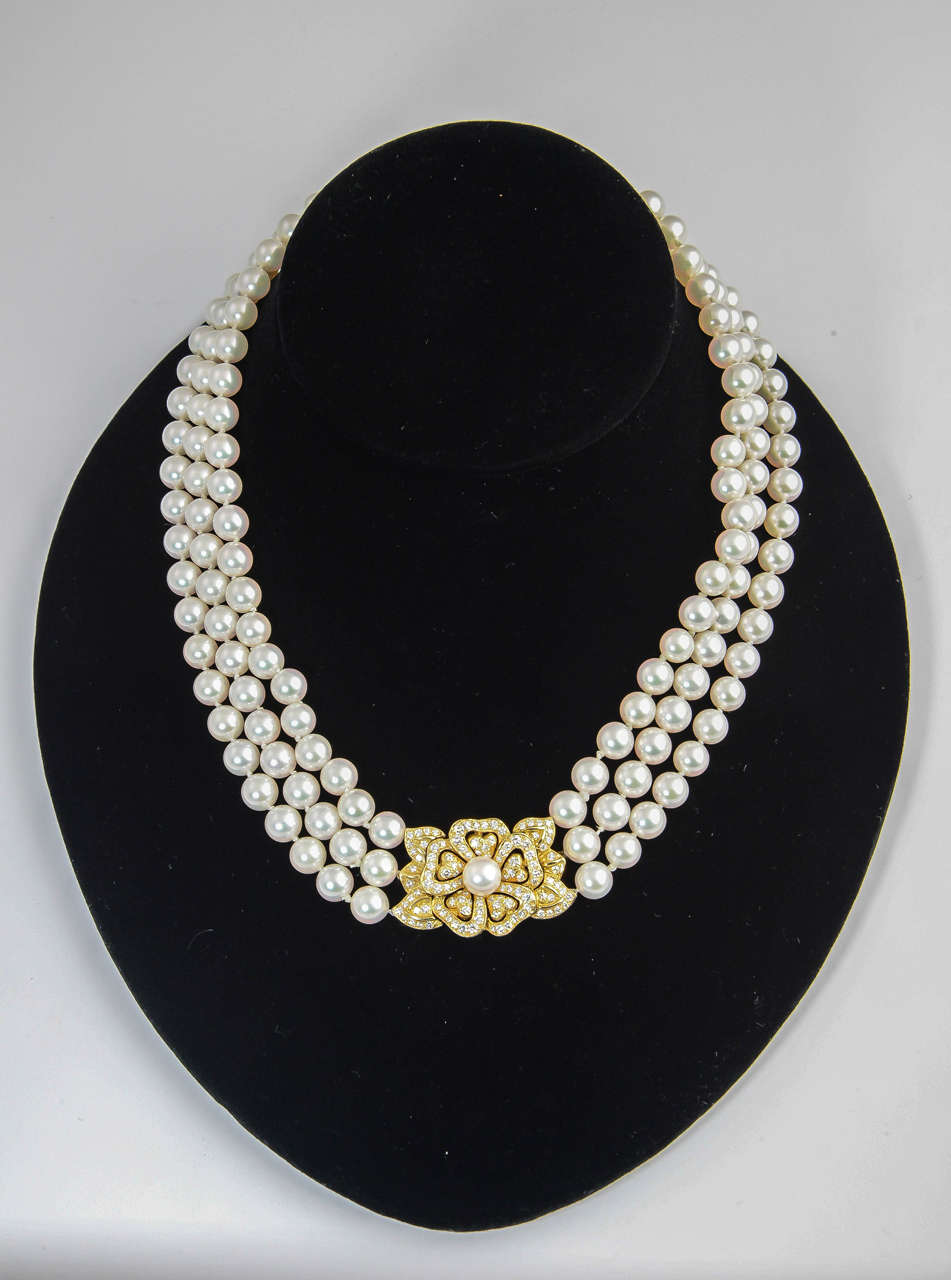 The necklace is made of 3 strands of beautiful approximately 7 mm pearls accented with a diamond and pearl floral piece.  It is marked with the Mikimoto 