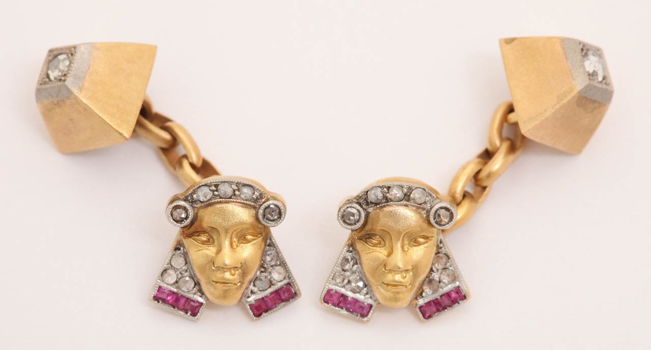 A wonderfully designed pair of cufflinks depicting a pharaoh's head and pyramid. Made of platinum topped gold, the pharoah's head is set with six calibre rubies and diamonds. His face is beautifully rendered in gold. The pyramid is set with one