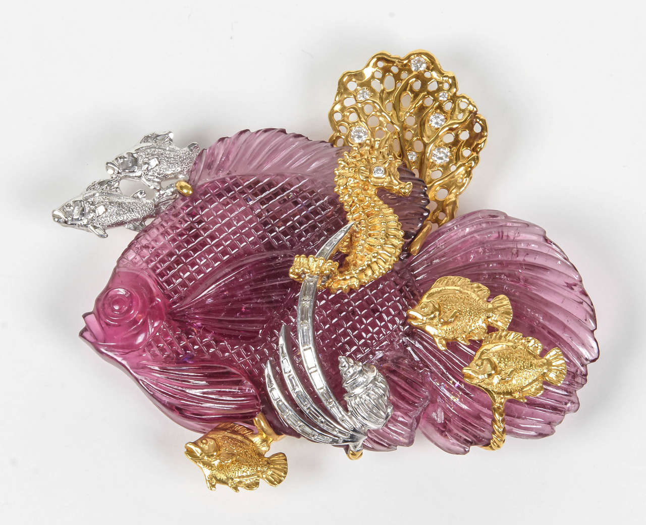 This one-of-a-kind large pin is designed around a slice of pink tourmaline exquisitely carved in Idar-Oberstein Germany. This fish is surrounded by other sea creatures in yellow and white gold, a sea fan in gold and diamonds and platinum and
