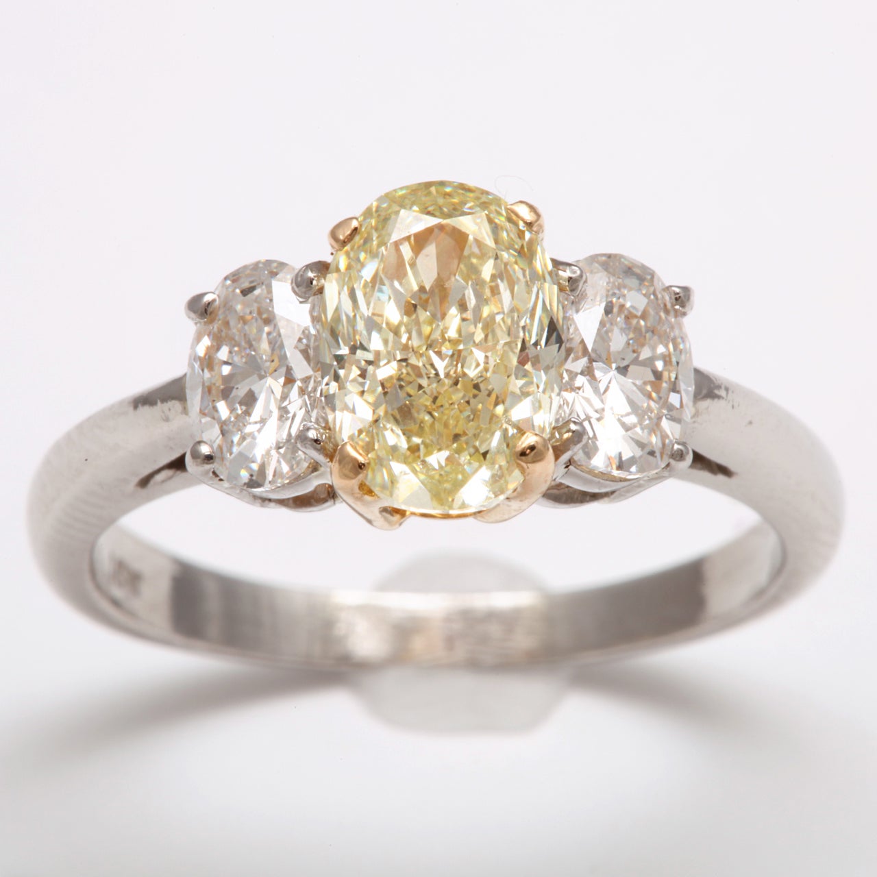 Gorgeous Fancy Light Yellow diamond, weighing 1.85 ct, GIA, VS2, flanked with two oval diamonds weighing approximately 1.17 cts, crafted in platinum & 18k gold.