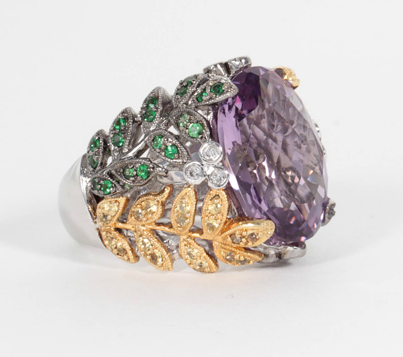 A one of a kind ring, beautifully designed.  

Center oval French cut Amethyst of over 11 carats. The center stone is set in 18k white and yellow gold and encrusted in emeralds, sapphires and diamonds.