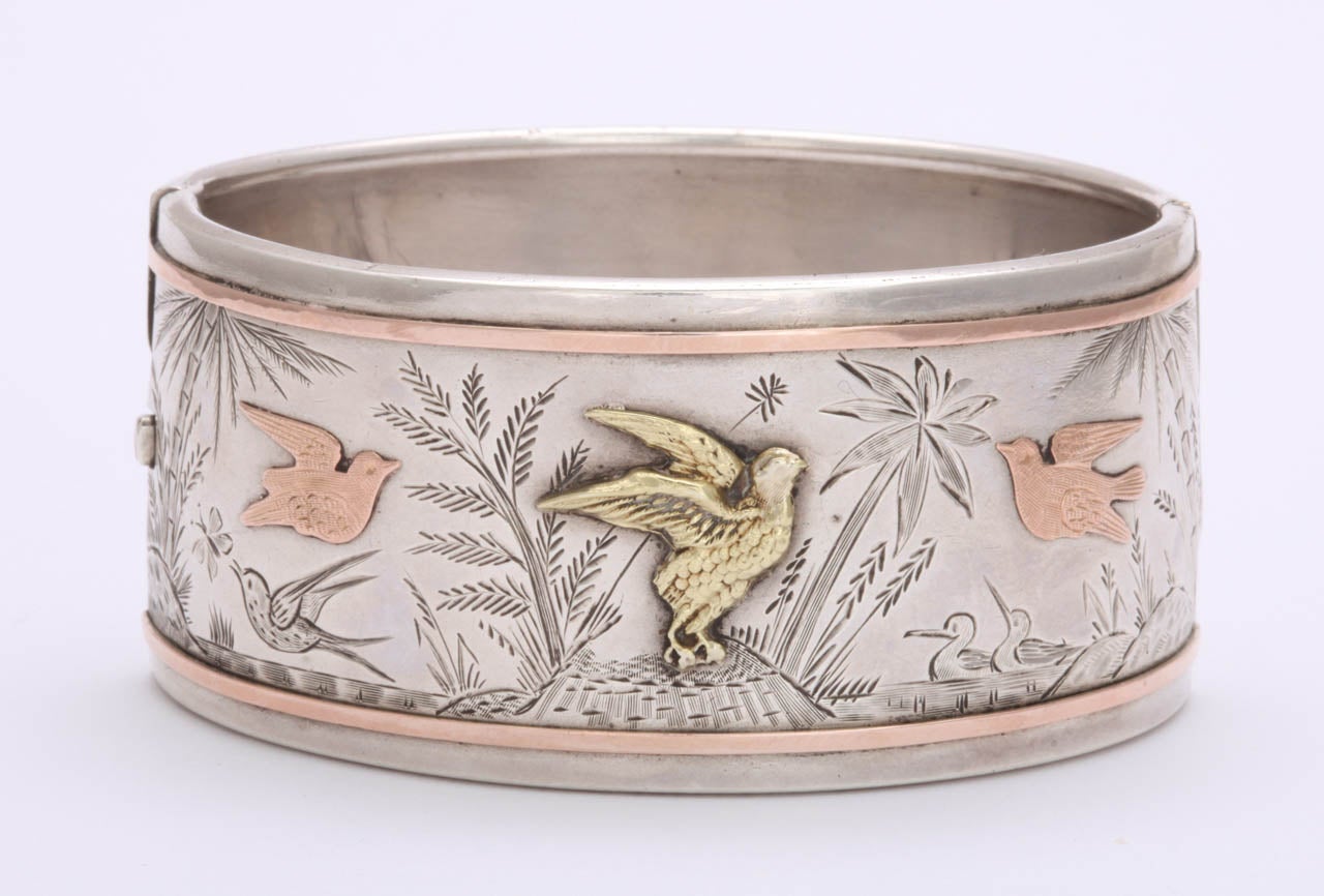With its pronounced rose gold borders and birds n flight the bracelet you see here is even stronger in design in person. It has movement in the engraved drawing of grasses and birds as if a strong breeze was present. It has the calm of the water