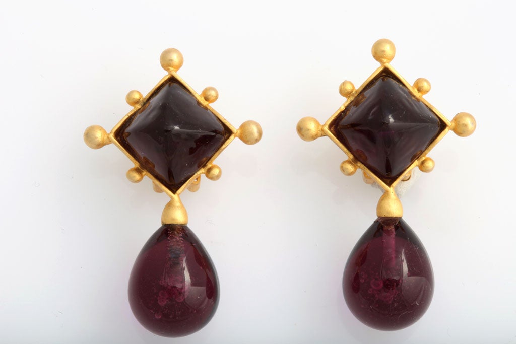 Purplish-black teardrop and goldtone earrings.