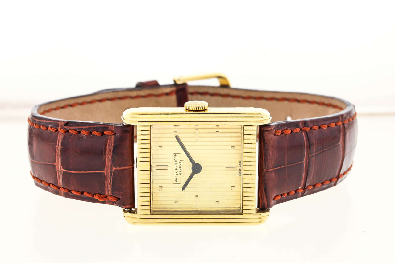 18K yellow gold Patek Philippe,Ref. 3467, produced circa 1965, is a fine, rectangular, 18K yellow gold wristwatch. The 28mm x 33mm case has a bezel with vertical fluted pattern. The gold dial repeats the vertical fluted pattern, applied gold dot and