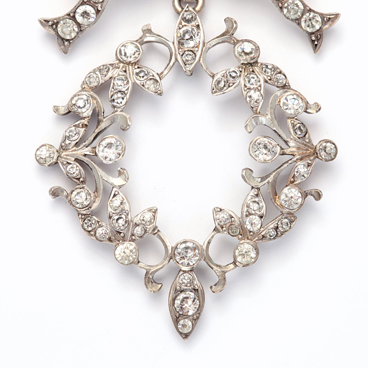 Graceful and unusual, with a bow as a reminder of affection, this silver and paste pendant was made in France in the Art Nouveau period when curves and swirls and garlands dressed architecture and ladies. The paste stones are a variety of sizes, a