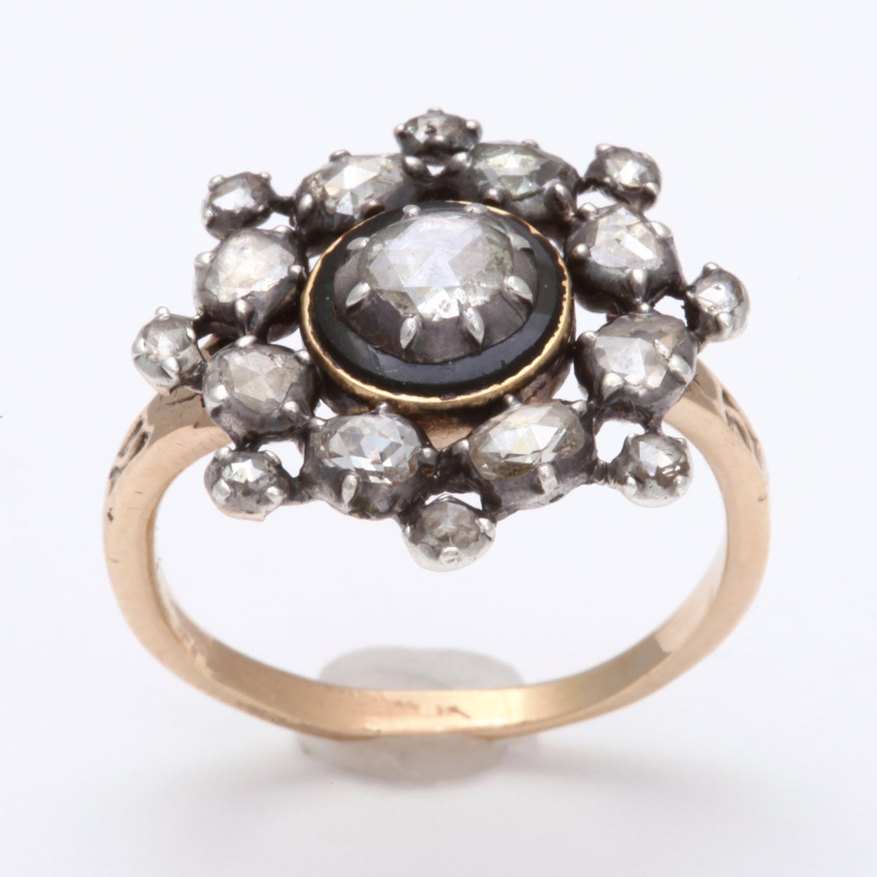 Sixteen antique cut diamonds form an irregular and graceful wreath that surrounds a one carat rose cut gem in this handmade Georgian Ring. The settings are silver rubbed over rounds with prongs. The central diamond shines  light from a gold frame