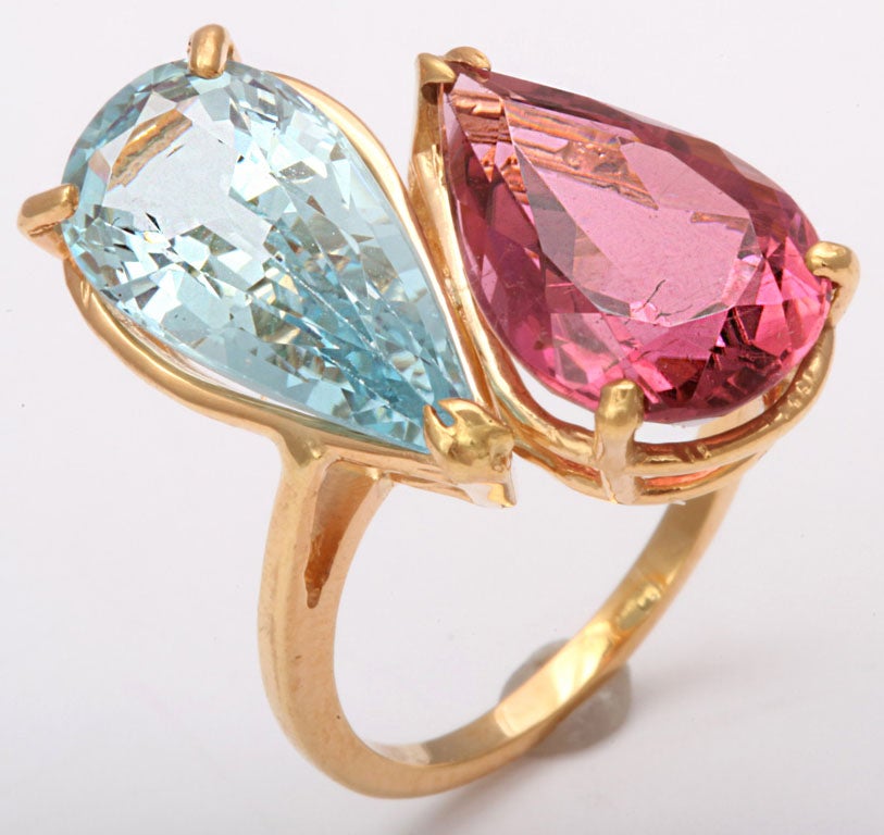This stunning toi et moi (you & me) 18k yellow gold ring was designed to highlight these beautiful colored stones.  The pink one is a pink tourmaline (rubellite) and the blue one is an aquamarine.  

Below is an article from The Jewelry Editor that