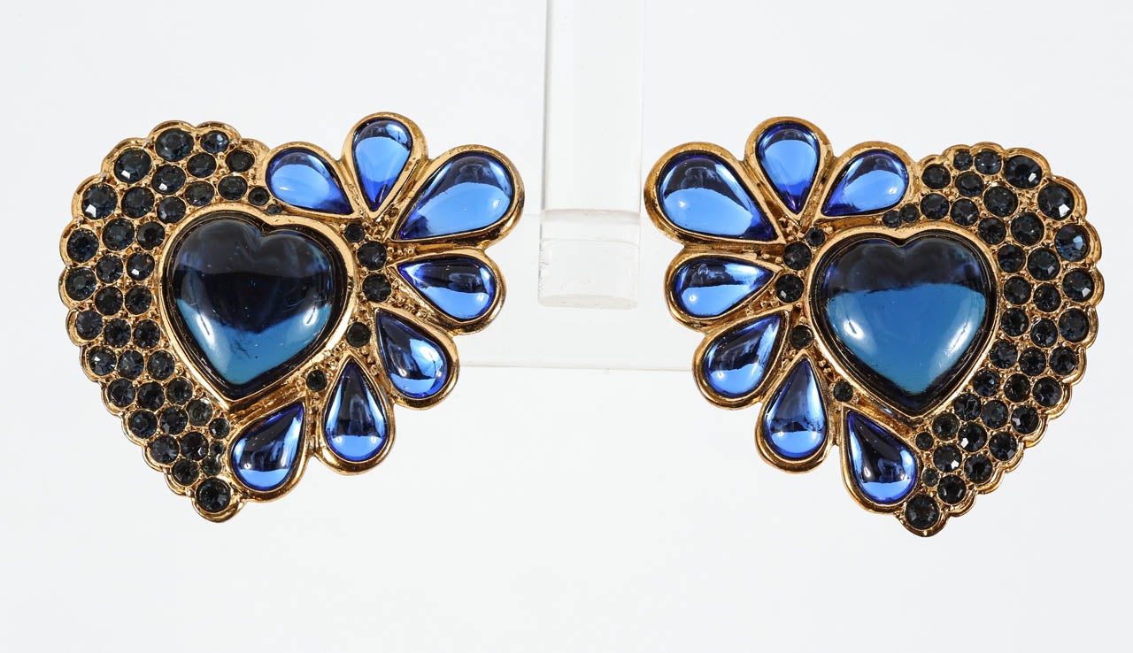 A glamorous pair of heart-shaped ear clips in gilt metal set with blue poured glass and blue rhinestones. Marked on the back with the 