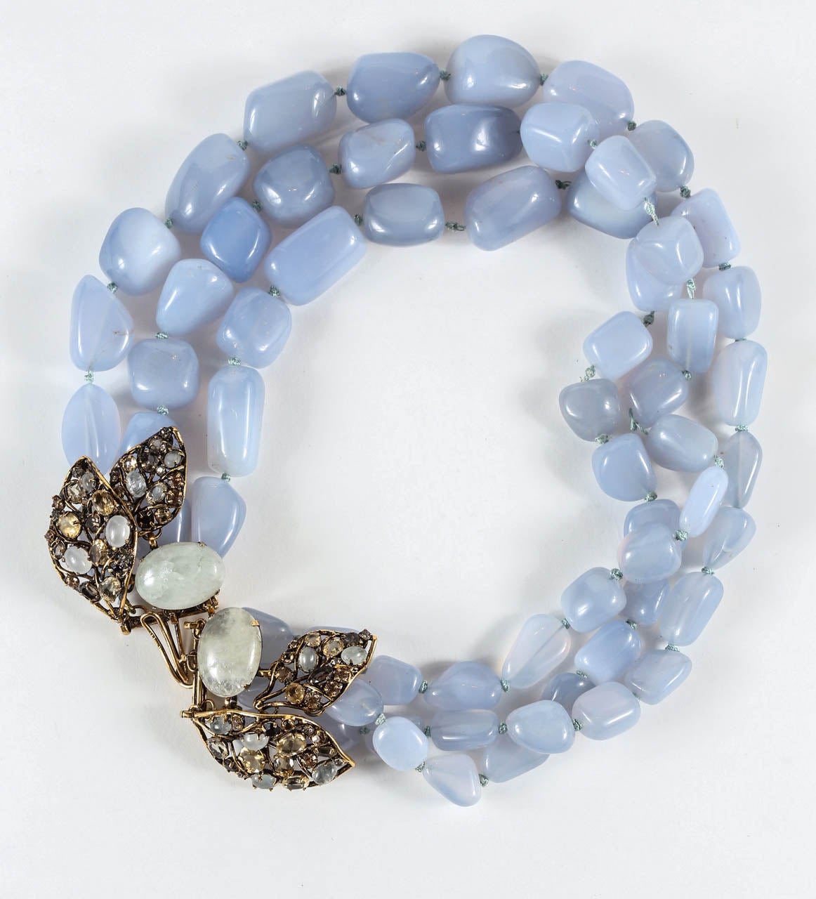A beautiful triple strand of large, irregular chalcedony beads with a brass clasp set with a pair of large quartz cabochons and leaves set with citrine, topaz, quartz & rhinestones. Although unmarked, this is unquestionably the work of Iradj Moini.