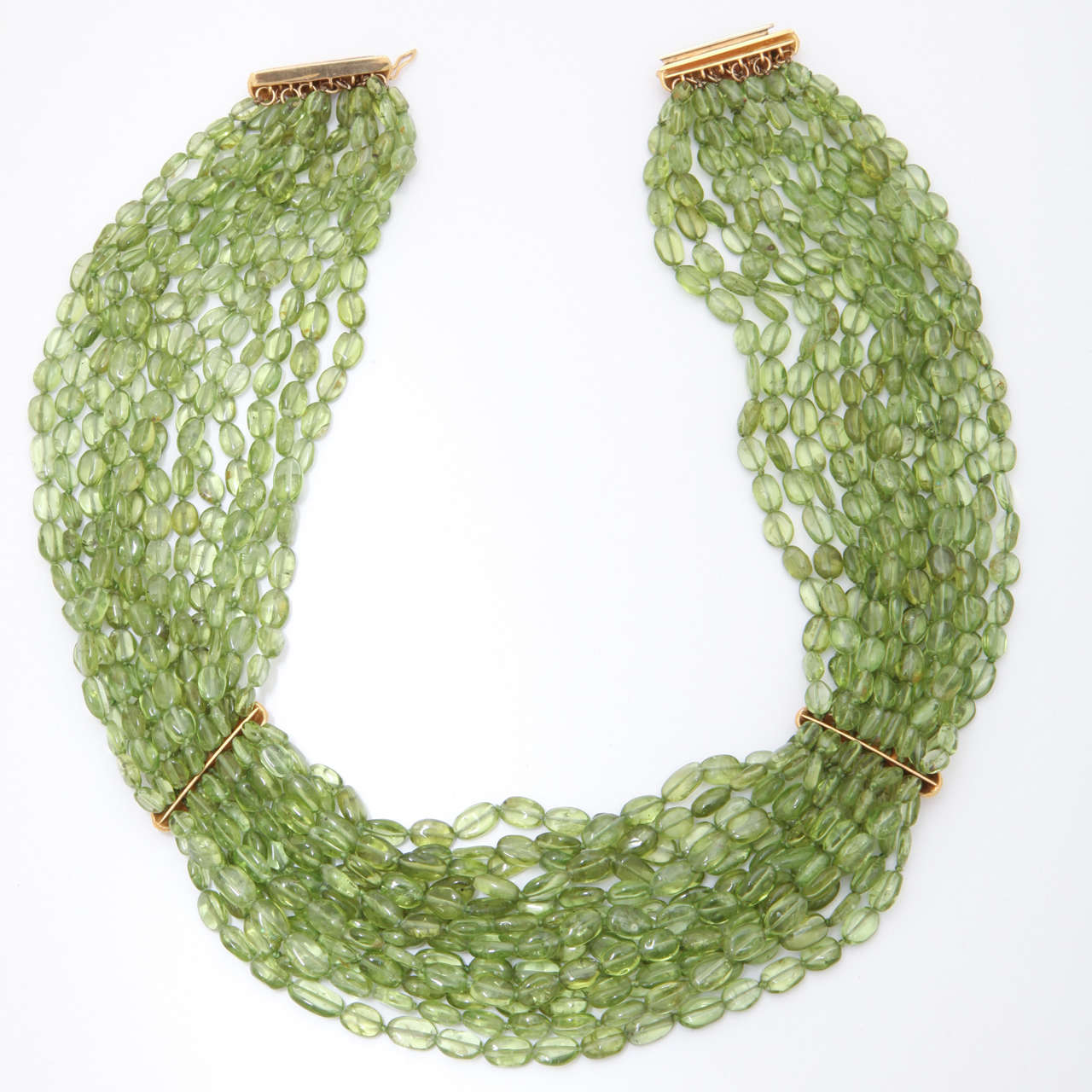 14 Strands of beautiful clear green peridot oval beads are divided into 3 sections by 18 kt pink gold bars. These bars are delicately carved with overlapping laurel leaves. The clasp is the same as the dividers and is a bayonet style where one bar