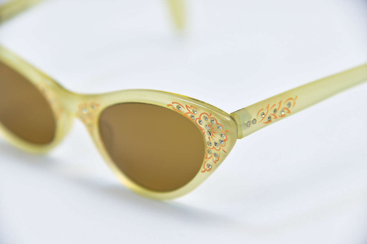 Extremely rare and timeless Schiaparelli shades!  These beauties are extremely well preserved. Accented with orange floral motifs and tiny rhinestones. Sure to turn heads. Collector's dream.

Frame Width: 127 mm
Bridge: 11.11 mm
Temple Arm