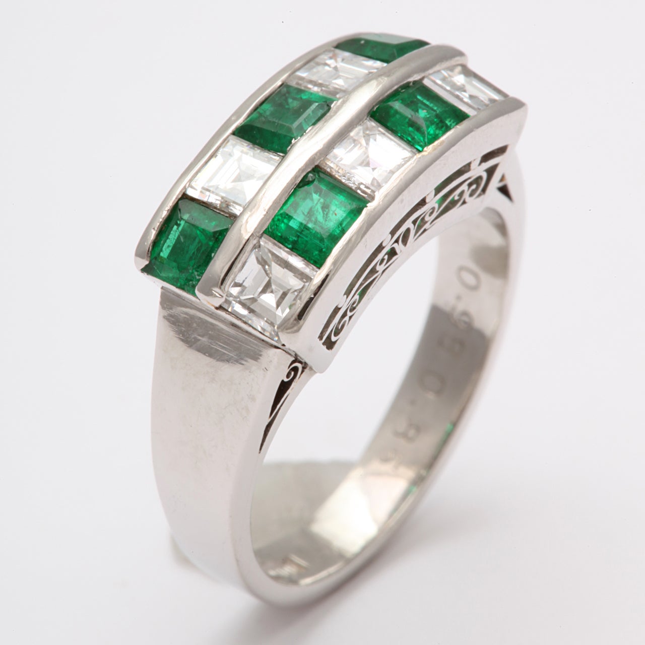 Alternating Emerald & Diamond Checkerboard ring with wide shank mounted on an elaborate Openwork Gallery.  Stones engraved  in the band as to size. Emeralds 95pts. Diamonds 85pts.  Inscribed 18ct