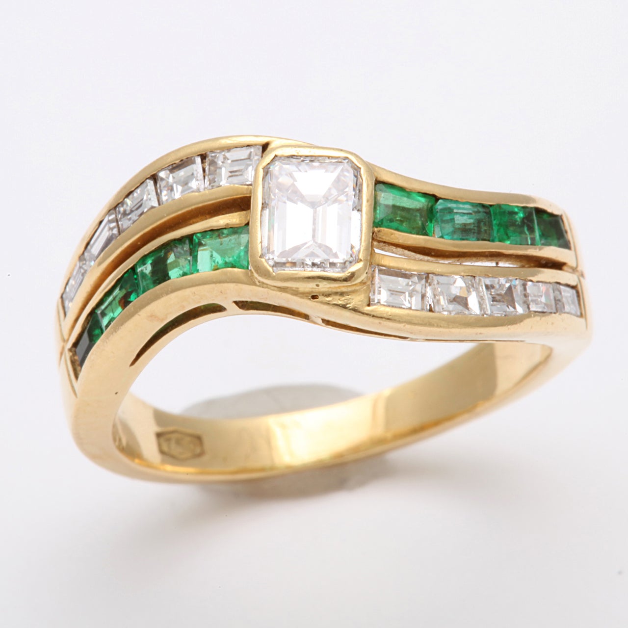 Center Bezel Set 95pt. Emerald cut Diamond  set with opposing Channel  Set Emeralds & Diamonds. Marked 750