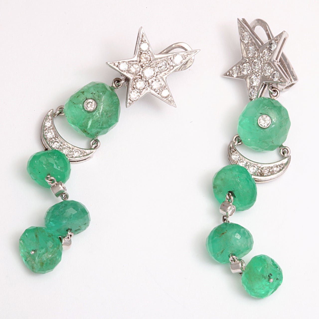 A fantastic pair of white gold earrings with faceted emeralds hanging from diamond encrusted moon and stars. French hallmarks