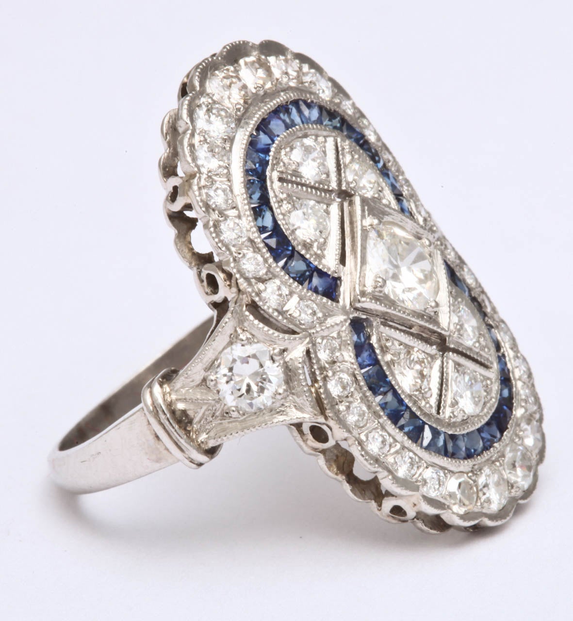 Platinum large cocktail dinner ring in the shape of a figure 8, embellished with numerous custom cut calibre cut sapphires and set with numerous old cut diamonds weighing approximately 1.50 cts; very high quality stones.