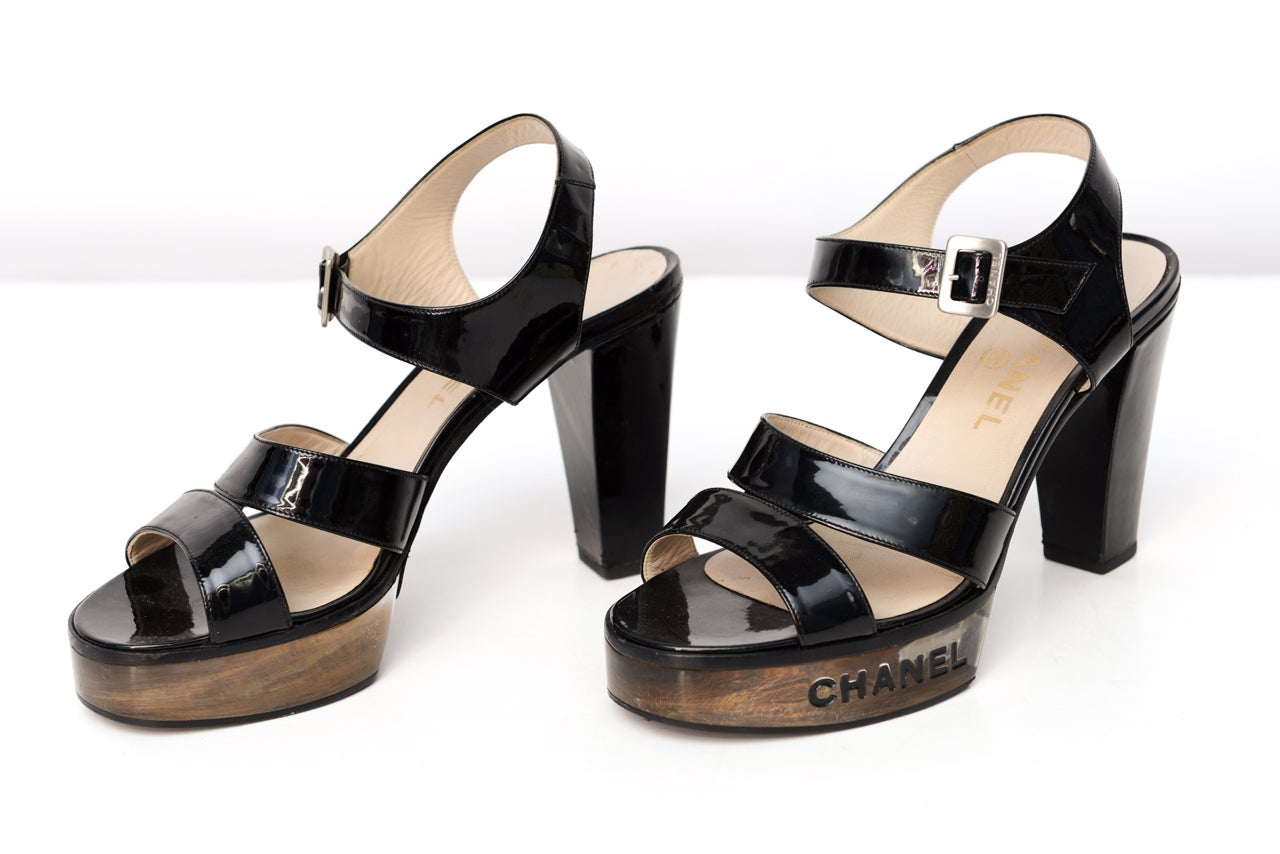 Set of vintage Chanel high heels that are see through clear and high gloss black. Chanel lettering in black on each side of shoe. Medium height heel. European size 39-40.