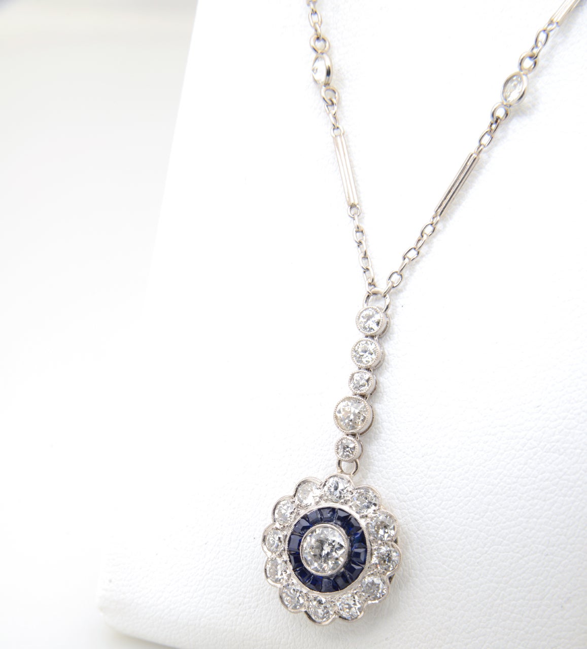 Finely made Art Deco diamond flower with a channel set sapphire ring around a .50 carat European cut diamond (approximate weight). The diamonds in the petals and drop are approximately another 1.5 carats.   The pendant measures  1 1/2