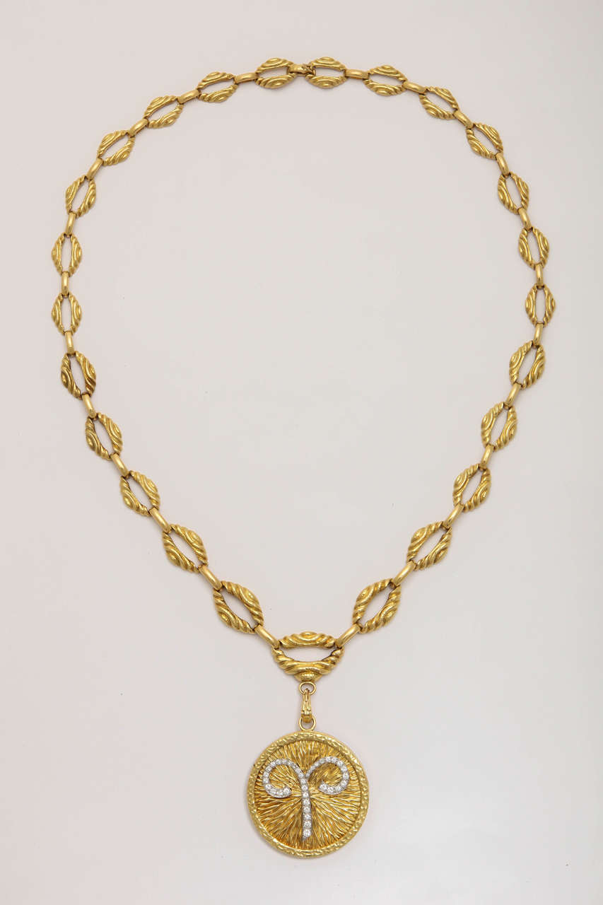 18k Gold textures round disc with astrological sign of Aries in diamonds. March 21 -April 19 is considered Aries.  There is a pin in the back. The chain can be worn on its own as the pendant is detachable. Both pieces signed David Webb.