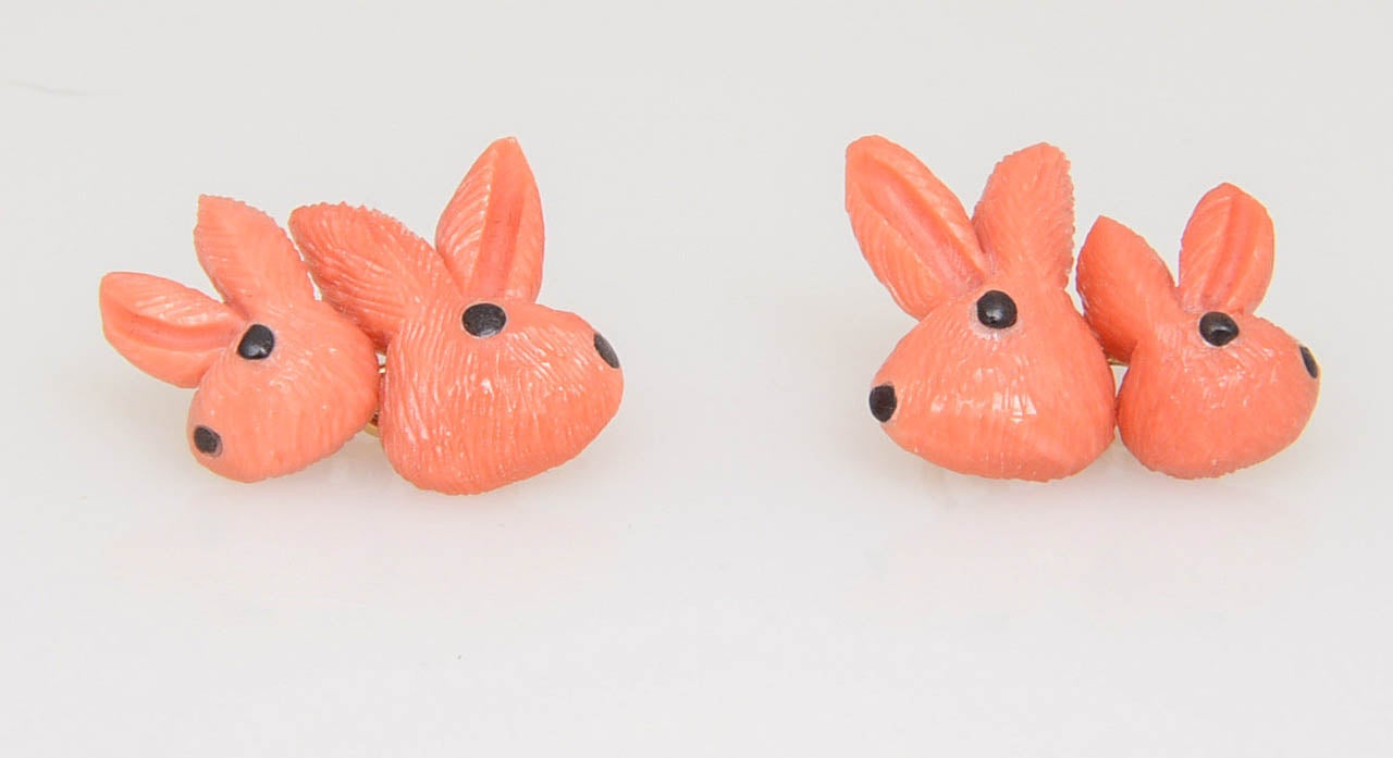 Finely hand carved coral rabbits with onyx eyes made in Italy.  The chain between them is 18k yellow gold.  The smaller bunny is .13