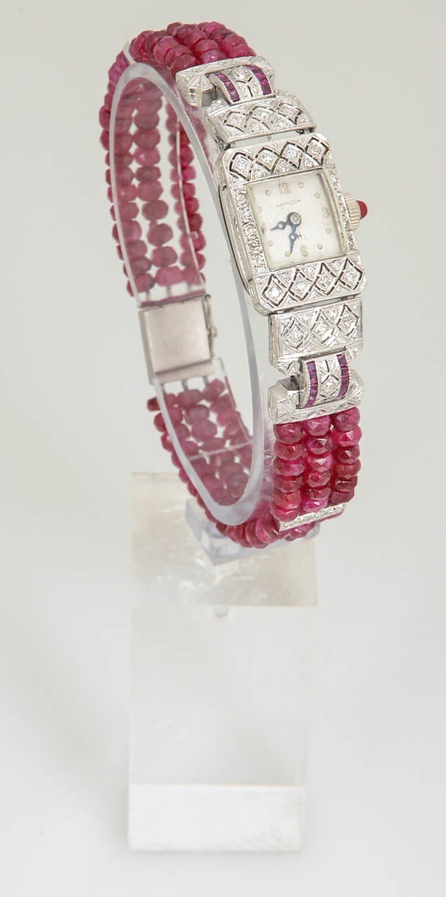 Fein gearbeitete Deco-Uhr mit geometrisch-filigranem Design:: besetzt mit Diamanten und Rubinen in Kanalfassung. Ein modernes Rubin-Perlenband mit Diamantabstandshaltern und eine neue Schließe machen dieses Schmuckstück zu etwas ganz Besonderem.