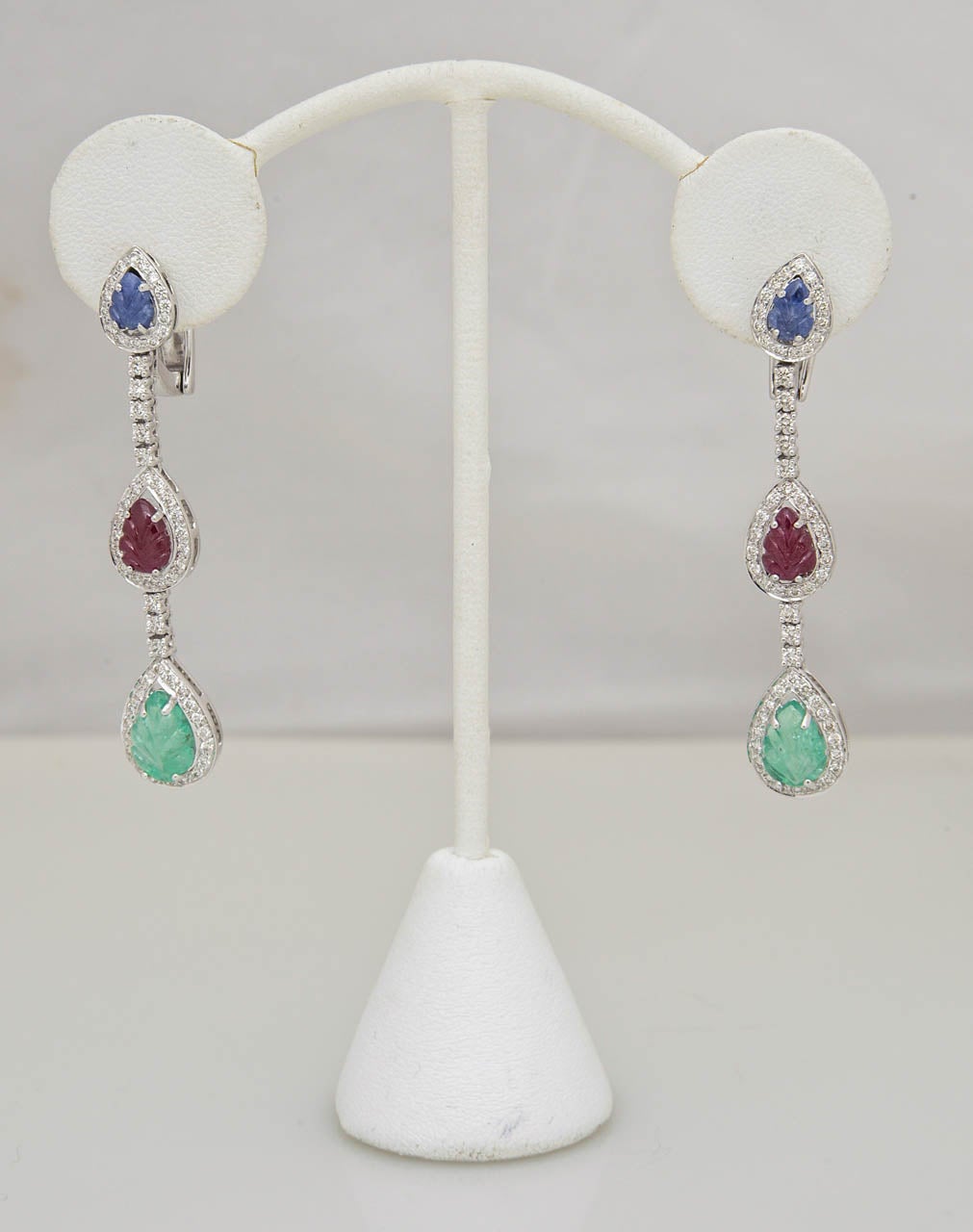 Contemporary Tutti Fruitti Style earrings with carved emerald, ruby and sapphire leaves set into diamond frames on a diamond chain set in 18k white gold.

Can be worn with or without the posts since the posts hinge down