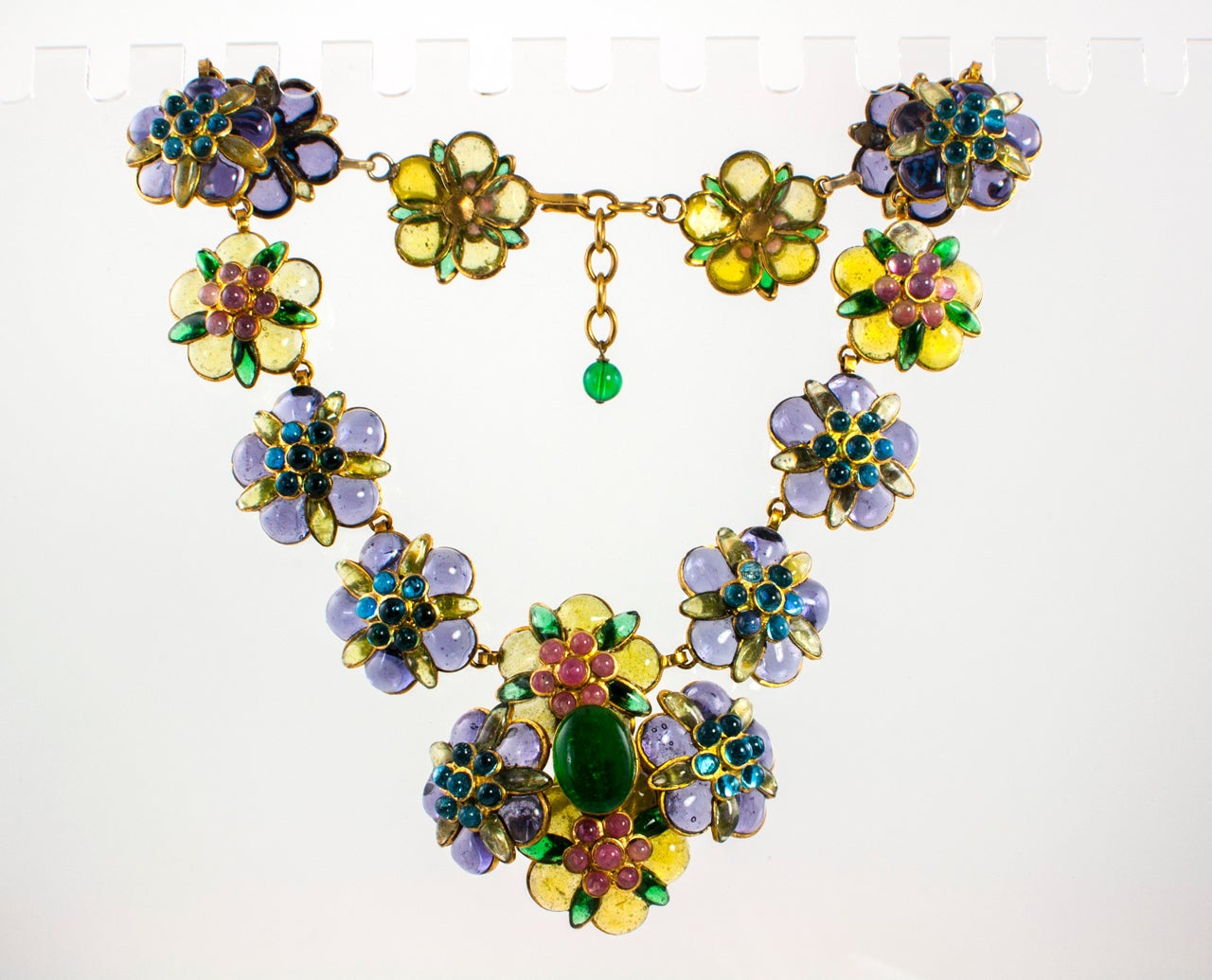 A elegant Gripoix necklace by Chanel featuring purple and yellow-green flowers accented with rose and blue centers and hints of green. The necklace is even more stunning in person than it appears in these images. Stamped on the back with the 