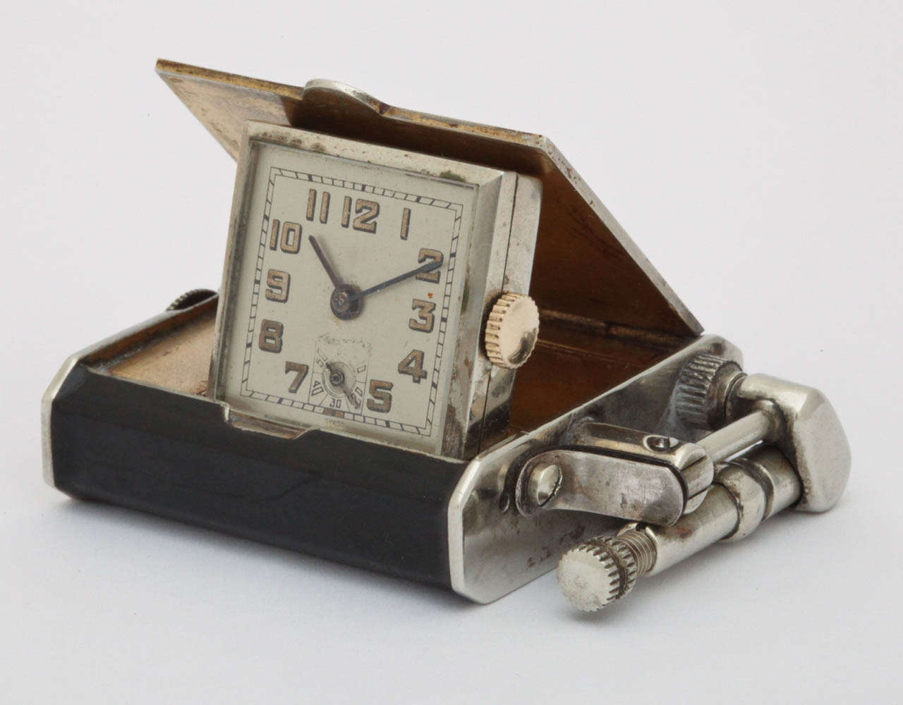 Hermann lighter with concealed watch. Square case is concealed in an enamel gold case with lift arm lighter. Watch in the center of the case concealed by a hinged door, Brevet 138381, 53mm x 40mm x 11mm.

Made in Switzerland by Hermann & Co., La