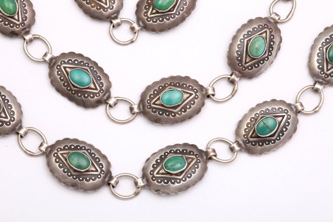 Natural turquoise set in each scalloped link of this Navajo belt was possibly made for a Native American Child.  Adult men and women wore large linked chunky belts.  Ours has a web of engraving on the artist signed clasp and circular patterns around