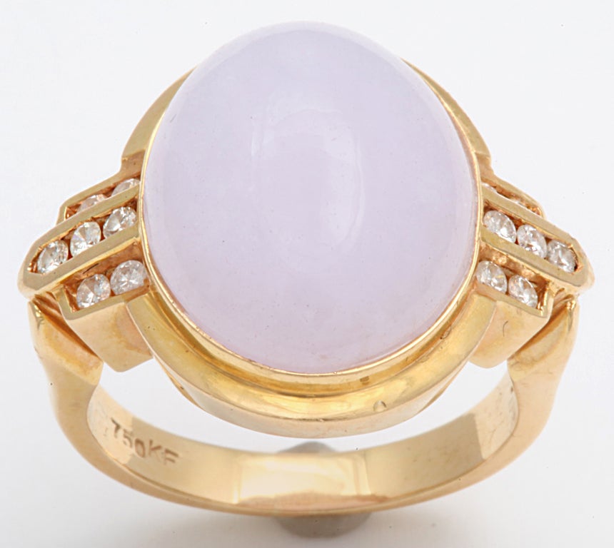 Lilac jade is the unusual color in this cabouchon oval cut lilac stone double framed in 18 kt gold. The shoulders are architectural buttresses set with fourteen diamonds. Though the jade gemstone comes in many colors, lilac jade is rare, The lilac