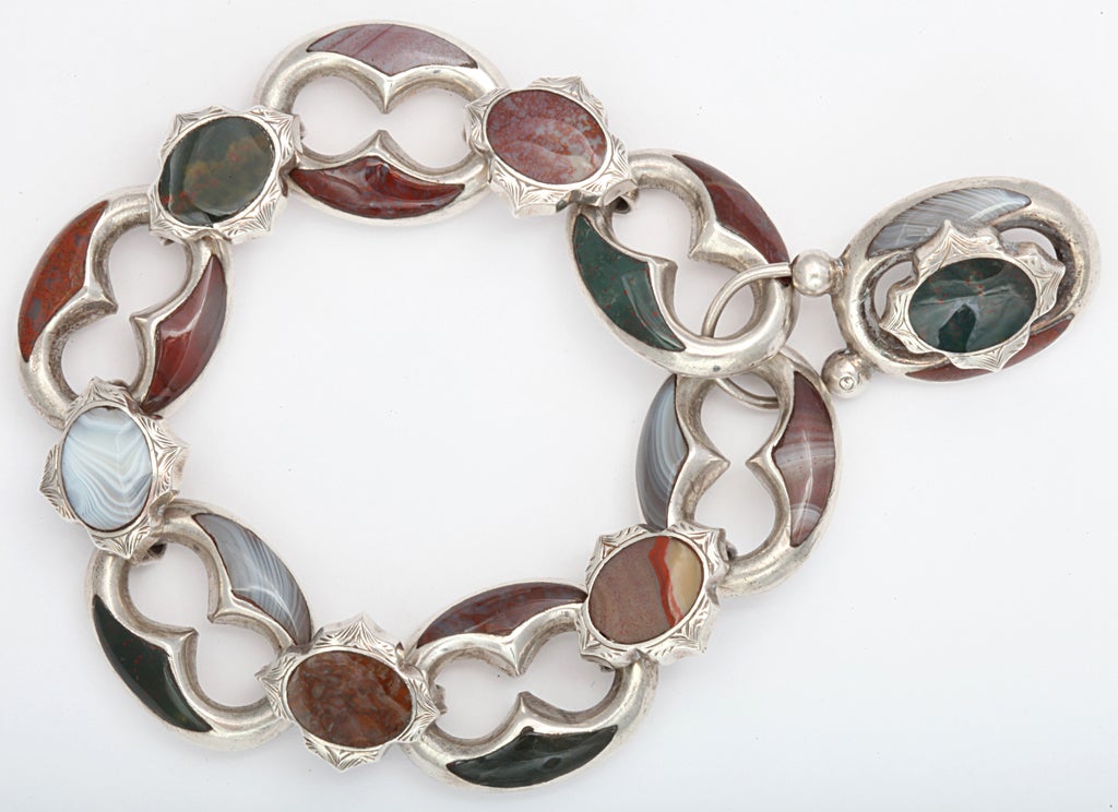 The favored figure eight link is inset with agates in the shape of crescents. Interest and flexibility are added by the shields that connect the figure eight ovals. Each shield is engraved around the agate center. The original padlock type clasp