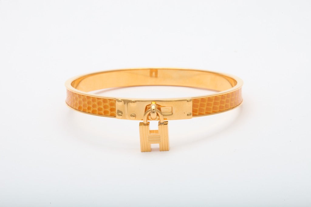 Hermes crocodile bangle with H charm in yellow with gold hardware.