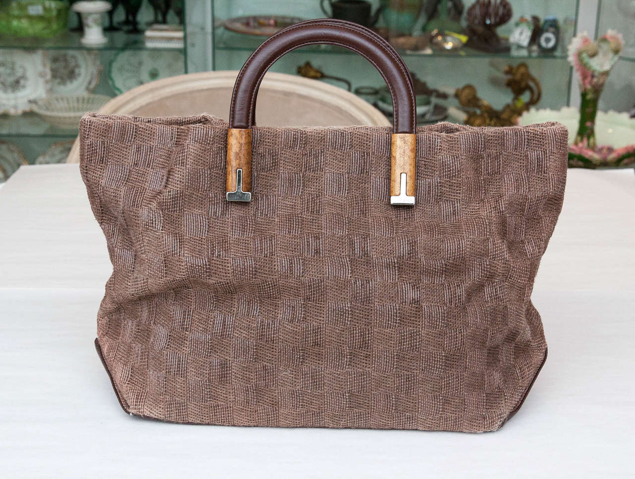 Unusual large Rodo brown handbag featuring sleek wood and metal accents on handles, extra sets of snaps to make bag smaller and larger, and an opulent checkerboard motif textile surround. Interior boasts a large lined compartment plus a zippered