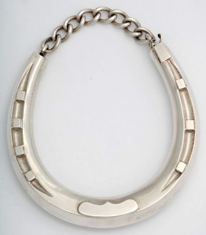 A sterling silver bangle in the form of a horseshoe complete with nail detailing. Fitted with a sterling silver chain and plunger clasp which makes this piece very easy to get on and off. Unsigned but most likely American. The opening measures 
1