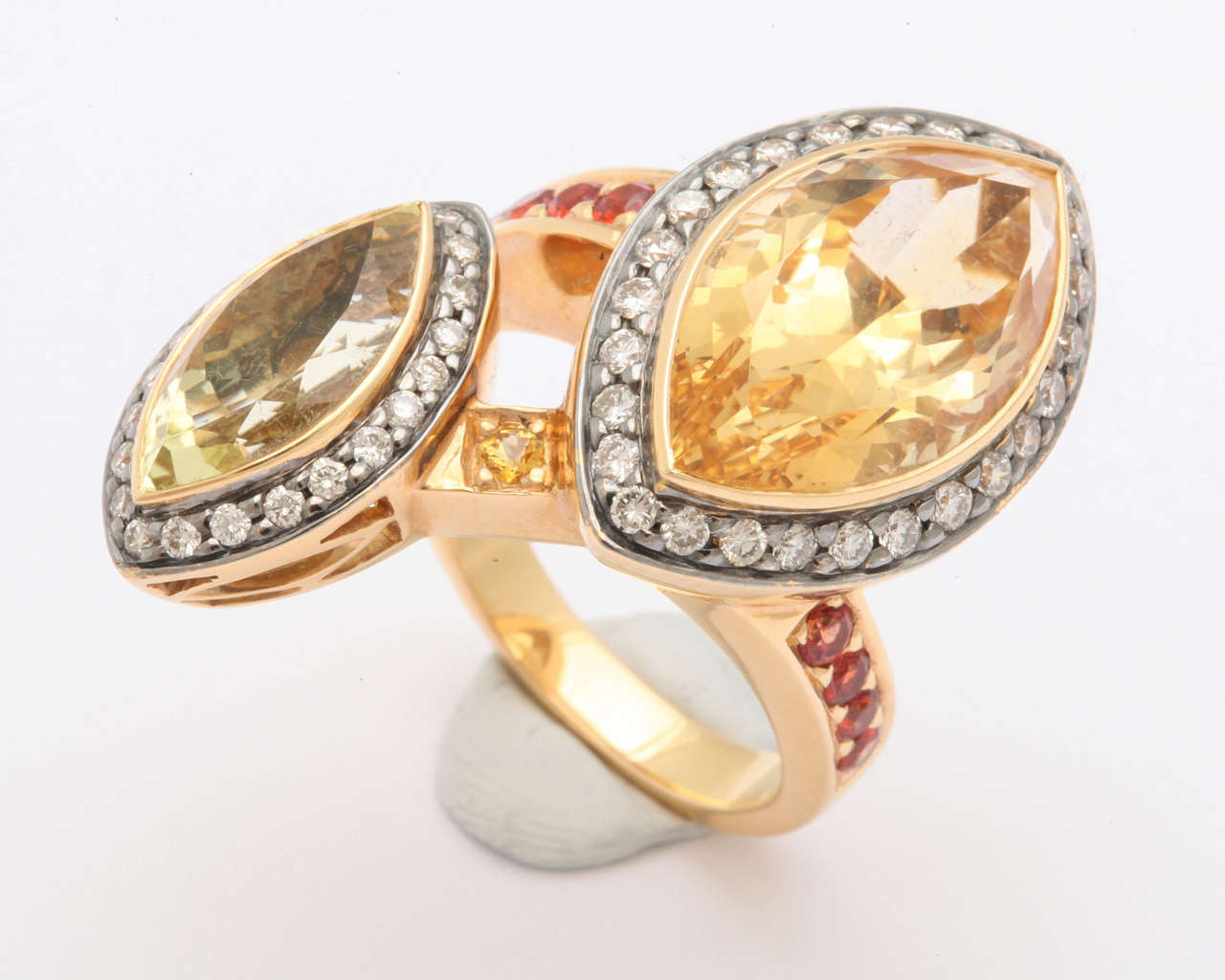 This magnificent bypass ring has an 8 ct marquise citrine and a 3 ct scapolite marquise. The main stones are surrounded by .75 ct white diamonds and .50 ct red-orange African sapphire going down the shank of the ring. The rinbg is size 7.5. A real